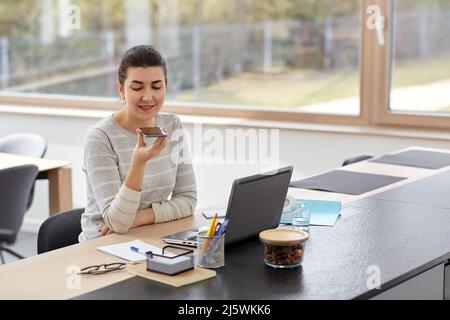 Frau mit Smartphone, die im Büro sprach Stockfoto