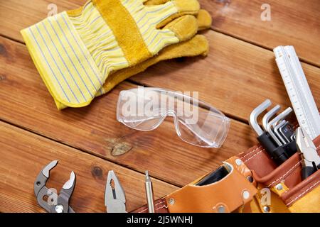 Verschiedene Arbeitswerkzeuge im Gürtel auf Holzbrettern Stockfoto