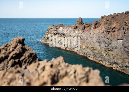 Schöner Strand mit schwarzen und dunklen Steinen und Kieselsteinen auf der Insel Lanzarote: Los Hervideros Stockfoto