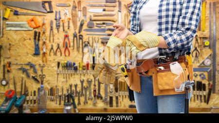 Frau oder Baumeister mit Handschuhen und Arbeitswerkzeugen Stockfoto