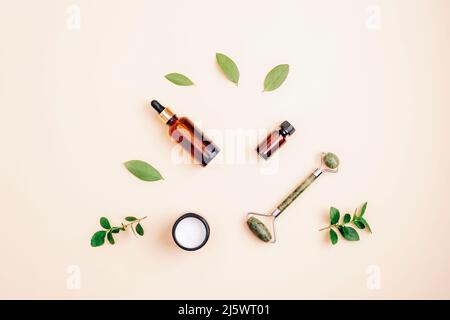 Moderne Apotheke, natürliche Inhaltsstoffe. Kosmetisches Serum, Creme, Gesichtswalze und ätherisches Öl. Draufsicht, flach liegend. Stockfoto