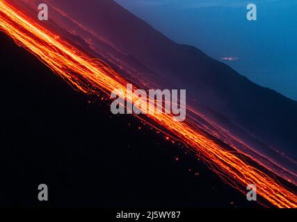 Glühende Lavabrocken kullern die Feuerrutsche des Stromboli hinab (sciara del fuoco). Langzeitbelichtung. Stockfoto