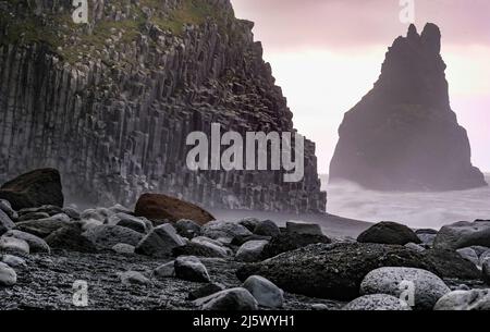 Schwarzer Strand Reynisfjara mit Basaltsäulen, Foto in der Morgendämmerung aufgenommen. Im Hintergrund einer der Reynisdrangar-Felsen. Stockfoto