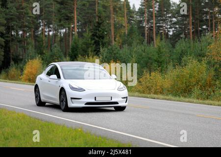 Weißes Tesla Modell 3 Elektroauto auf Landstraße an einem Herbsttag. Salo, Finnland. 25. September 2020. Stockfoto