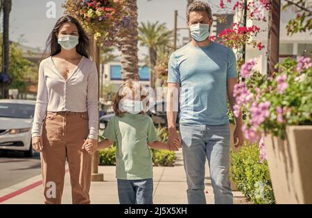 Familie während der Coronavirus-Pandemie. Eltern mit Kind Junge tragen medizinische Maske. Stockfoto