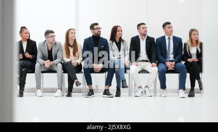 Eine Gruppe von verschiedenen Geschäftsleuten applaudieren in einer Reihe sitzen. Stockfoto