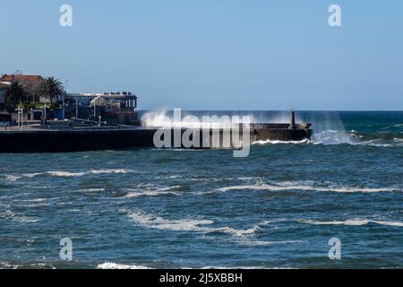 Wellen schlagen an einem sonnigen Tag gegen den Hafen von lekeitio in der kantabrischen See Stockfoto