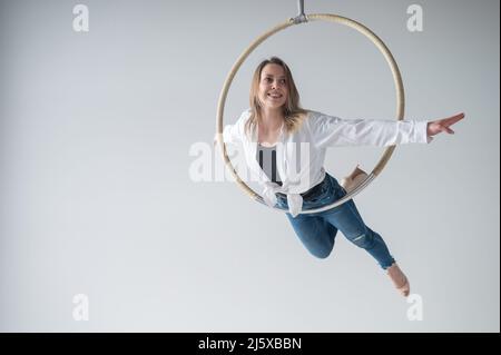 Kaukasische Frau in legerer Kleidung und High Heels Schuhe auf Air Hoop. Stockfoto