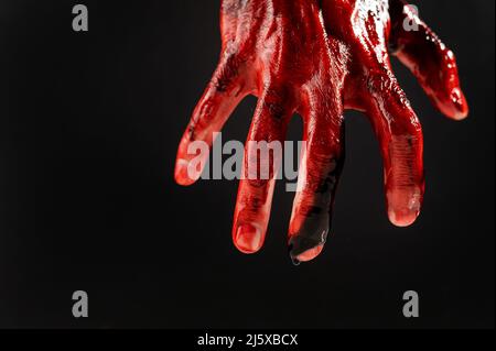 Nahaufnahme einer mit Blut befleckten männlichen Hand auf schwarzem Hintergrund. Stockfoto