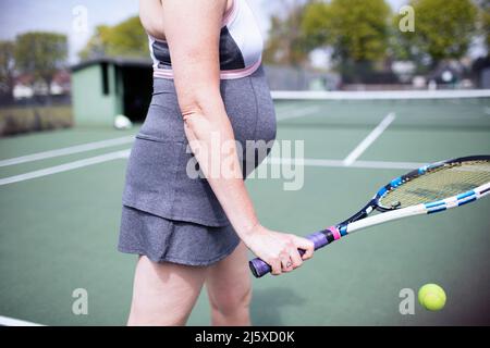 Eine Schwangerin spielt Tennis auf dem Tennisplatz Stockfoto