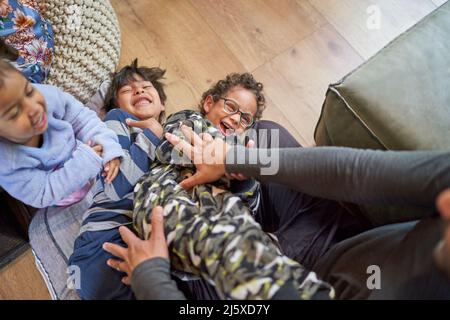 Verspielter Vater kitzelt Kinder Stockfoto