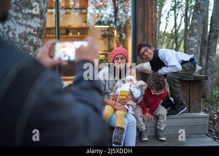 Glückliche Familie posiert für Foto außerhalb Hütte in Wäldern Stockfoto