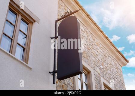 Großes schwarzes vertikales Schild an der Straßenfassade. Modell für Promotion, Branding und Logo-Präsentation Stockfoto