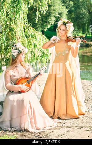 Duett von Frauen, die in der Natur Gitarre und Violine spielen Stockfoto