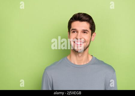 Foto von lustigen Millennial Brunet guy suchen leeren Raum tragen graues Tuch isoliert auf grünem Hintergrund Stockfoto
