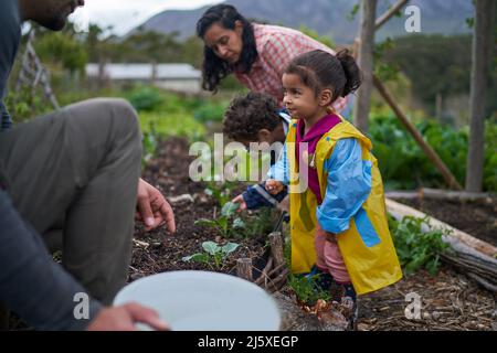 Nettes Kleinkind Mädchen im Garten mit Familie Stockfoto