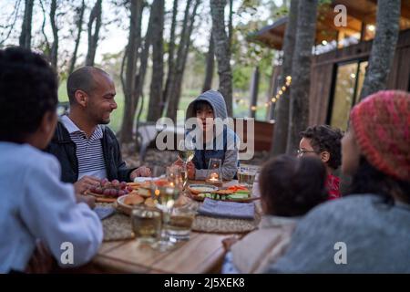 Familie, die am Tisch draußen in der Hütte im Wald isst Stockfoto
