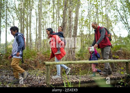 Familie überquert Fußgängerbrücke auf Wanderung im Wald Stockfoto