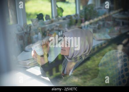 Lächelnde junge Frau, die im Kunststudio Keramik malt Stockfoto