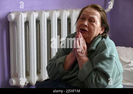 DOVHOPOLE, UKRAINE - 25. APRIL 2022 - eine alte Frau lebt in der Turnhalle einer örtlichen Schule, in der Vertriebene aus der Region Kiew, Dowhopol, ihre Heimat hatten Stockfoto