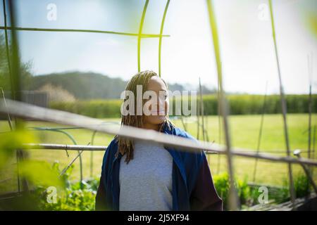 Lächelnde junge Frau im sonnigen Garten Stockfoto