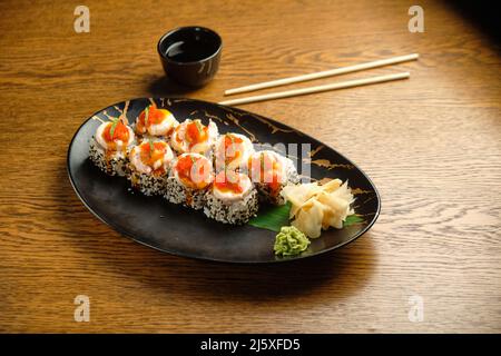 Sushi-Rollen mit Lachs, Kaviar, Avocado und schwarzem Sesam in Nahaufnahme. Selektiver Fokus Stockfoto