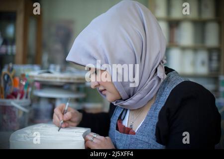Junge muslimische Künstlerin, die im Kunststudio arbeitet Stockfoto