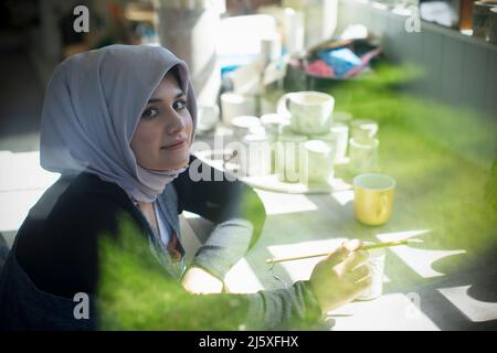 Portrait selbstbewusste junge muslimische Künstlerin im Kunststudio Stockfoto