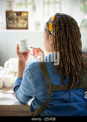Junge Künstlerin Malerei Keramik Becher Stockfoto