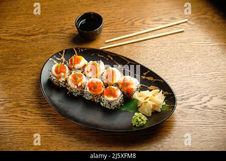 Sushi-Rollen mit Lachs, Kaviar, Avocado und schwarzem Sesam in Nahaufnahme. Selektiver Fokus Stockfoto