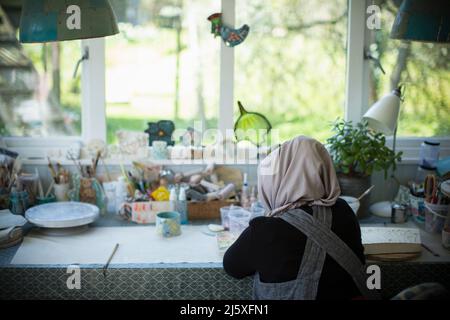 Junge Künstlerin in Hijab, die im Kunststudio arbeitet Stockfoto