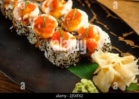 Sushi-Rollen mit Lachs, Kaviar, Avocado und schwarzem Sesam in Nahaufnahme. Selektiver Fokus Stockfoto