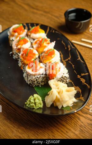 Sushi-Rollen mit Lachs, Kaviar, Avocado und schwarzem Sesam in Nahaufnahme. Selektiver Fokus Stockfoto