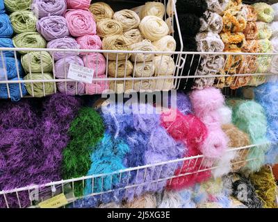 Set aus bunten Fäden und gewebten Stoffen in den Regalen im Geschäft. Russland, Omsk, 17.12.2019 Stockfoto