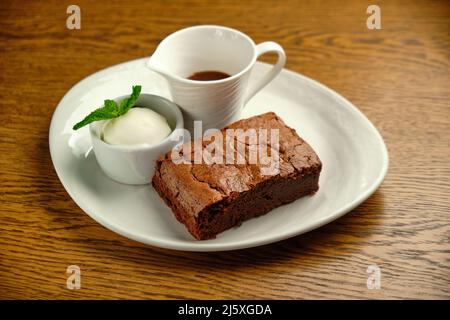 Schokoladenkuchen auf einem Holztisch mit Eis und Minzblatt auf der Oberseite, Restaurantkarte Stockfoto