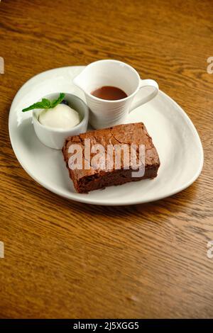 Schokoladenkuchen auf einem Holztisch mit Eis und Minzblatt auf der Oberseite, Restaurantkarte Stockfoto