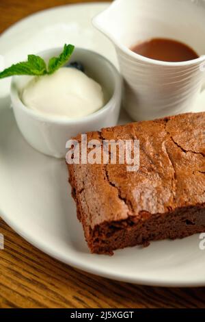Schokoladenkuchen auf einem Holztisch mit Eis und Minzblatt auf der Oberseite, Restaurantkarte Stockfoto