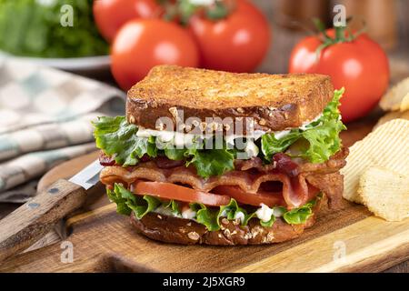 BLT-Sandwich mit Speck, Salat und Tomaten auf geröstetem Vollkornbrot auf einem Holzbrett Stockfoto