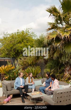 Ein paar Freunde unterhalten sich auf dem Sofa auf der Terrasse Stockfoto