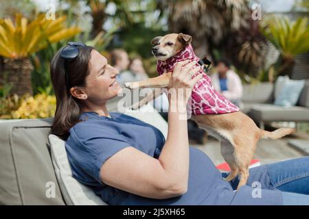 Glückliche, schwanger Frau mit Hund auf der sonnigen Terrasse Stockfoto