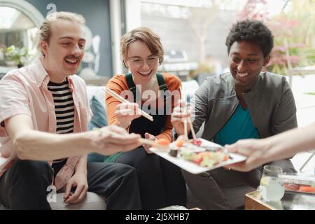 Glückliche Freunde teilen sich das Sushi-Mittagessen Stockfoto