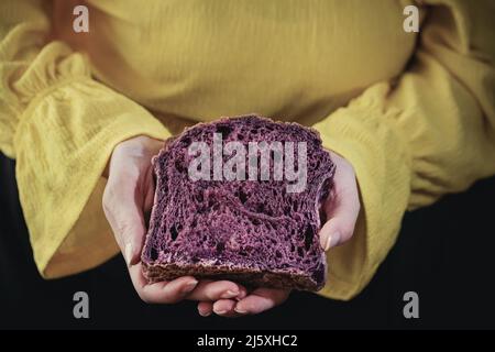 Eine junge Frau hält ein Stück Bio-Brot, das aus roter Karotte, Nahaufnahme, Stillleben Fotografie Stockfoto