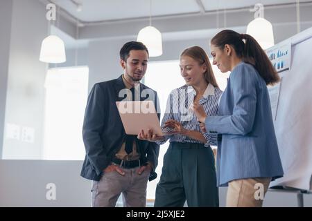Team von jungen Fachleuten bei einer Tagung im Konferenzraum mit Blick auf Laptop. Stockfoto