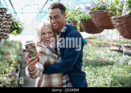 Glückliches Paar, das Selfie im Gartenladen macht Stockfoto