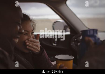 Glückliches Paar trinkt Kaffee im Auto Stockfoto