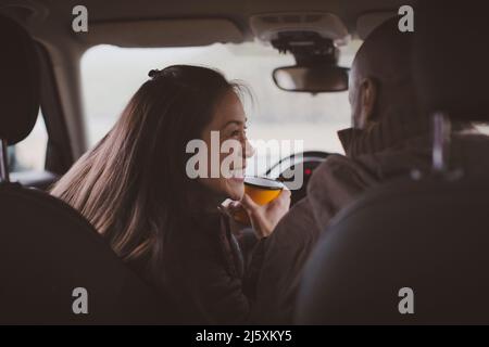 Glückliches Paar trinkt Kaffee im Auto Stockfoto