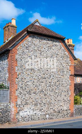 Alte Mauer mit einer Mischung aus Feuerstein und rotem Backstein, an einer großen Wand an der Seite eines Gebäudes in England, Großbritannien. Stockfoto