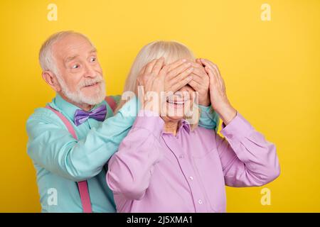 Porträt von zwei attraktiven fröhlich grauhaarigen Ehegatten schließen Augen Vorbereitung Geschenk isoliert über hellen gelben Hintergrund Stockfoto