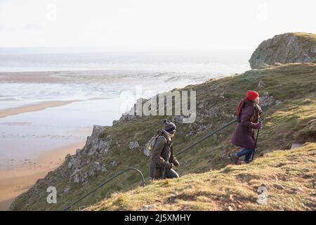 Ein Paar Wanderer klettert auf einer Klippe über dem Strand Stockfoto