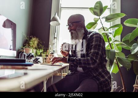 Leitender Mann, der am Computer im Heimbüro arbeitet Stockfoto